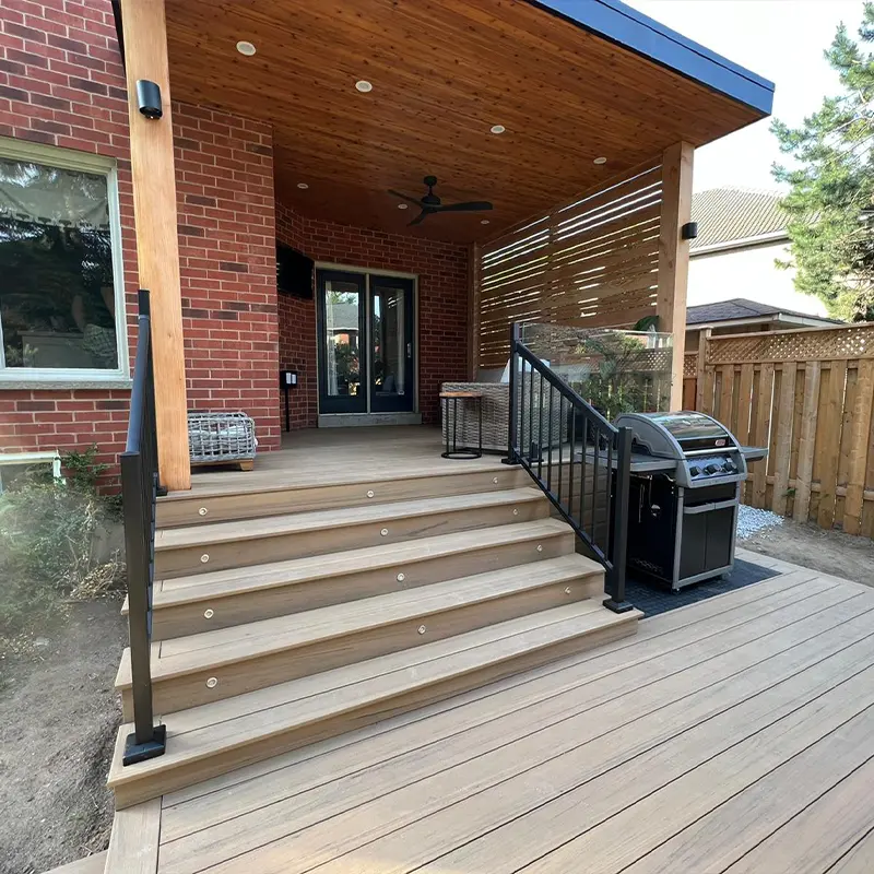 Custom covered backyard porch with composite stairs and black aluminum railing by Megapol Deck in GTA.